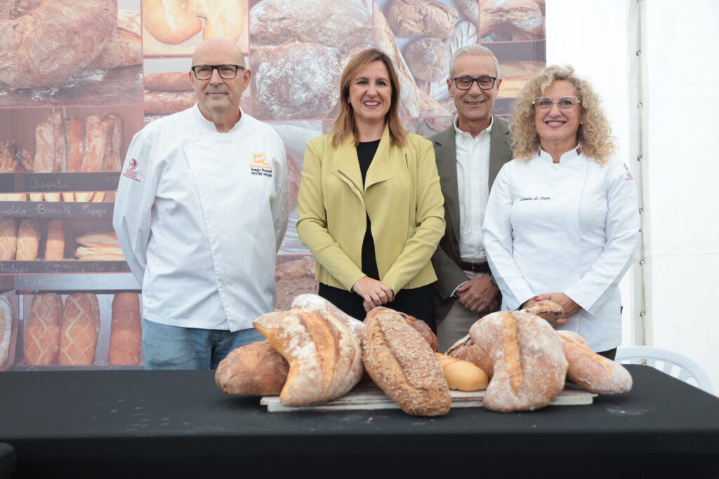 Autoridades y maestros panaderos junto a una tabla de panes artesanos