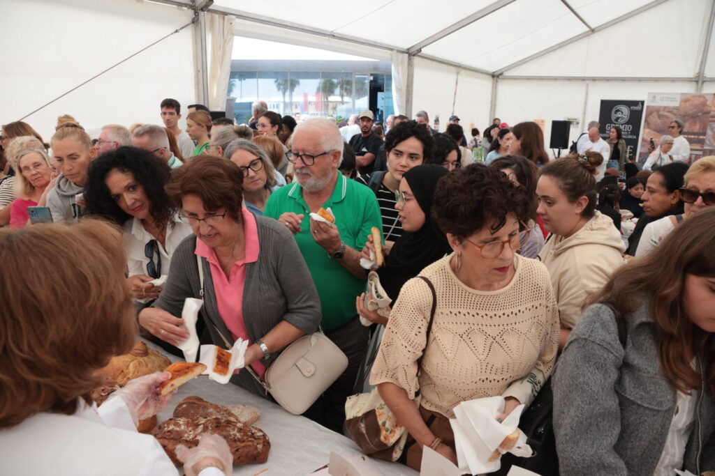 Público de todas las edades degustando pan en la carpa de la feria